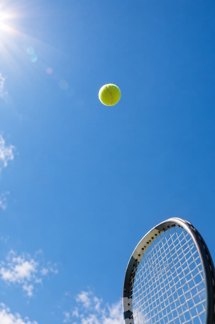 Serve toss against a blue sky
